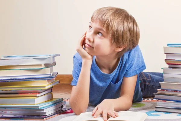 Rapaz sorridente entre as pilhas de livros . — Fotografia de Stock
