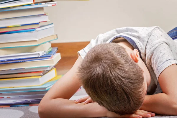 Cansado menino perto de grande pilha de livros . — Fotografia de Stock