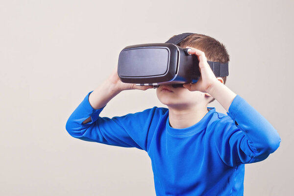 Мальчик в очках виртуальной реальности смотрит фильмы или играет в видеоигры
