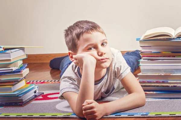 Bored child lying between piles of books — Stock Image Bored child lying between piles of books Stock Picture