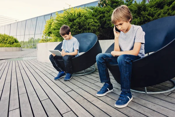 Två barn med surfplatta och smart telefon i staden utomhus. — Stockfoto