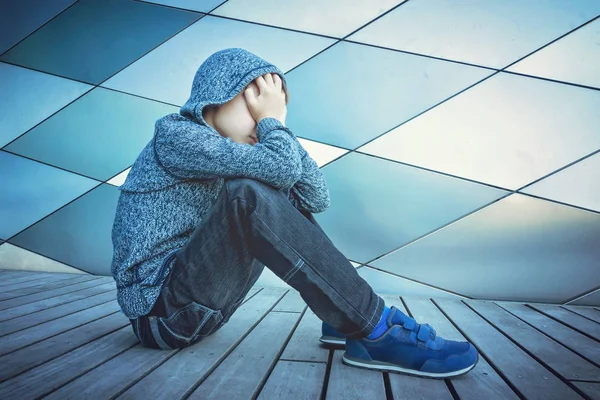 Triste, solitario, infeliz, niño decepcionado sosteniendo la cabeza con las manos sentadas solas en el suelo al aire libre — Foto de Stock