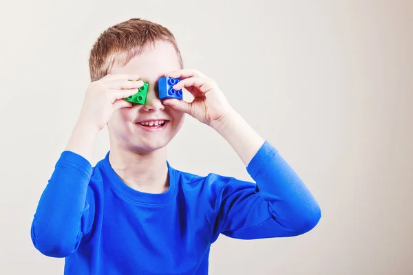 Criança feliz brinca com blocos de brinquedo de plástico colorido . — Fotografia de Stock