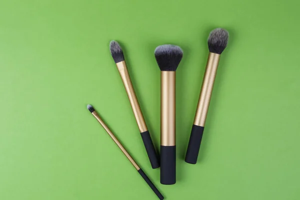 Maquillaje cepillos sobre fondo verde — Foto de Stock