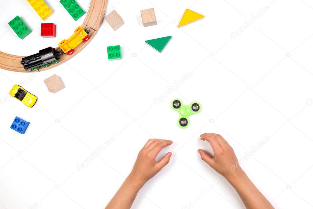 Kids hands playing with fidget spinner toy. Many colorful toys on white background.