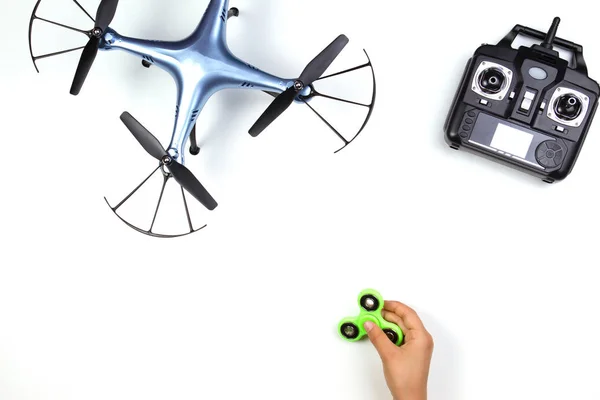 Las manos de los niños jugando con el juguete fidget spinner. Drone y mando a distancia sobre fondo blanco . — Foto de Stock