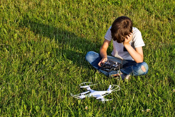 Jongetje zittend op het gras met drone. — Stockfoto