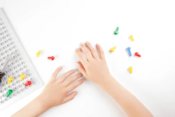 Vue du dessus sur les mains des enfants jouant avec des jouets colorés outils sur le fond blanc . — Photo