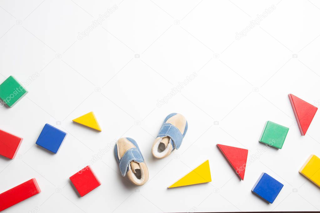 Colorful wooden blocks and baby shoes on white background