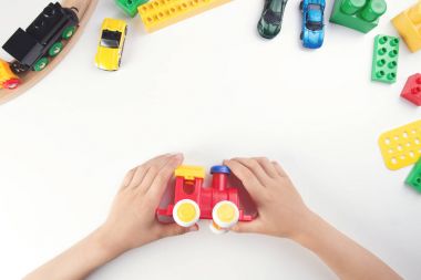 Childs'ın ellerinde oyuncak tren ve beyaz masa arka plan üzerinde birçok oyuncakları ile oynarken Üstten Görünüm.