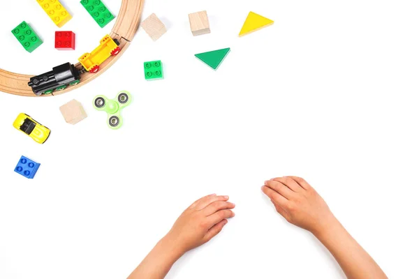 Crianças mãos e brinquedos coloridos. Fidget spinner, carros, trem de brinquedo, tijolos e blocos no fundo branco — Fotografia de Stock