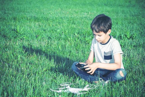 Niño con dron sentado en la hierba . — Foto de Stock
