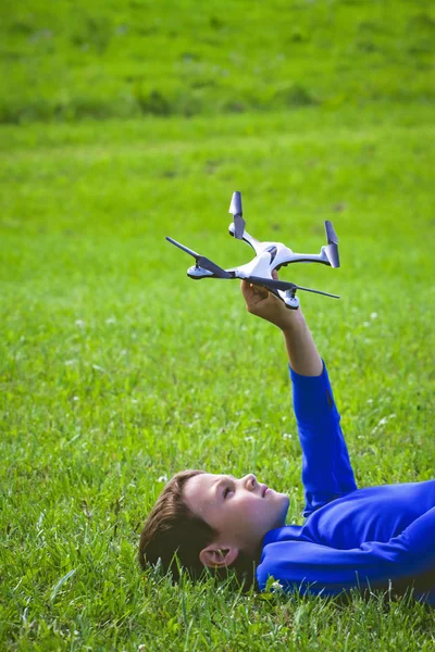 Niño con dron acostado en la hierba al aire libre . — Foto de Stock