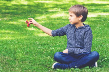 Çimenlerin üzerinde oturan spinner çocukla