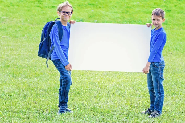 Crianças com placa de cartaz branco em branco ao ar livre — Fotografia de Stock