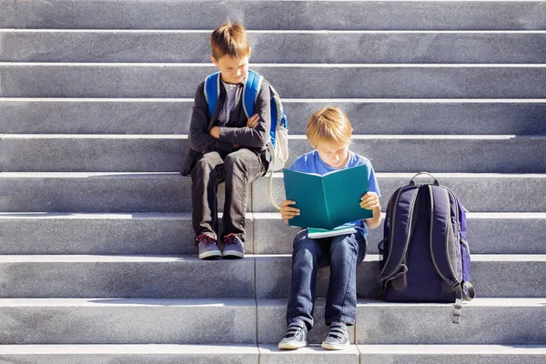 Dos chicos leyendo, haciendo deberes al aire libre. Regreso al concepto escolar . — Foto de Stock