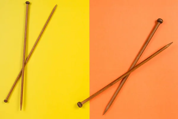 Agulhas de tricô de madeira marrom no fundo amarelo e laranja — Fotografia de Stock