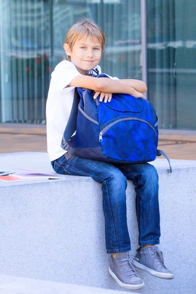 Χαμογελώντας μαθητής κάθεται με το σακίδιο του εξωτερική. Εκπαίδευση, επιστροφή στο σχολείο, έννοια του ταξιδιού — Φωτογραφία Αρχείου