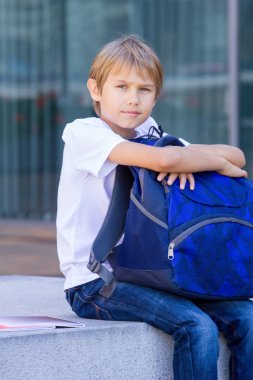 Okul çantasını açık oturan gülümsüyor. Eğitim, okul, seyahat konsepti için