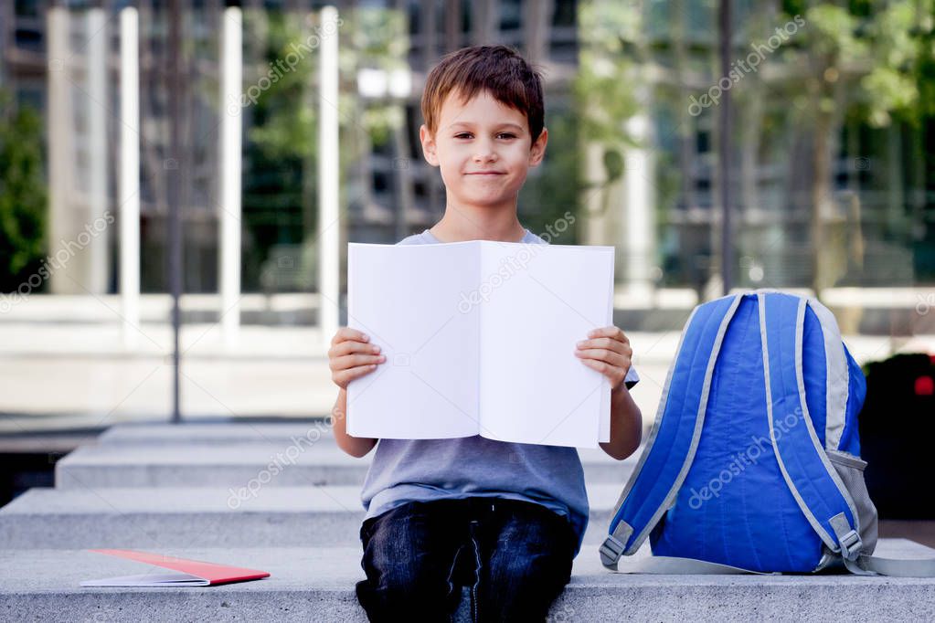 Little boy holding blank open notebook with copy space for text