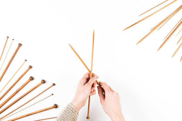 Knitting background. Woman hand and wooden knitting needles on white background
