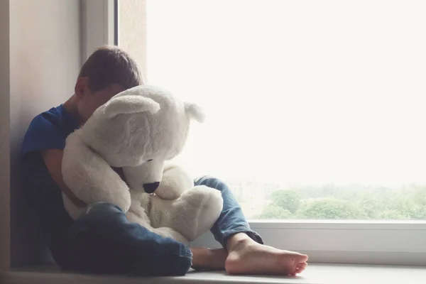 pencere üzerinde oturan üzgün çocuk