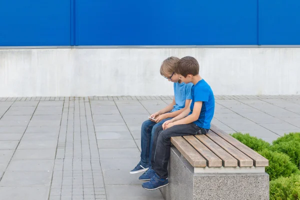 모바일 게임의 작은 소년 두 개 벤치 야외에 앉아 전화 — 스톡 사진