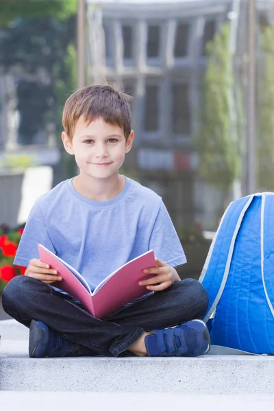 Kind lezen boek en huiswerk buitenshuis — Stockfoto