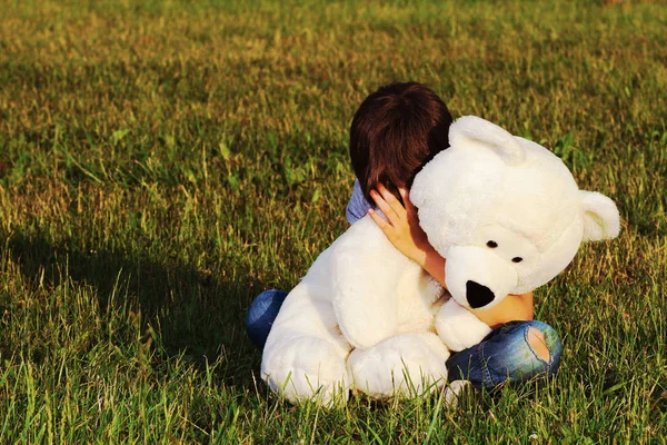 Açık havada oturma ve oyuncak ayı sarılma üzgün çocuk — Stok fotoğraf