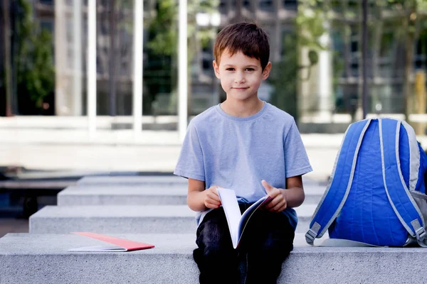 Παιδί κάθεται στον πάγκο και να ρίχνεις μέσα από τις σελίδες του βιβλίου σε εξωτερικούς χώρους — Φωτογραφία Αρχείου