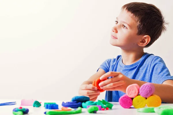 Menino jogando e criando a partir de argila de modelagem ou plasticina — Fotografia de Stock