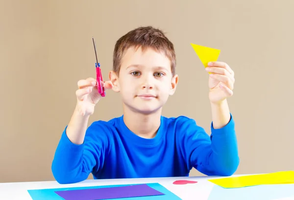 Ragazzo taglio carta colorata con forbici a tavola — Foto Stock