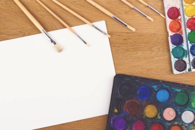 Suluboya boyalar, ahşap arka plan resim ve boş beyaz kağıt kağıda için fırçalar.