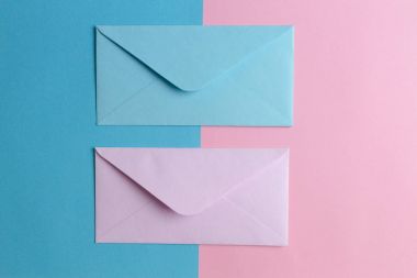 Pembe ve mavi zarfların pembe ve mavi renkli arka plan üzerinde. Üstten Görünüm.