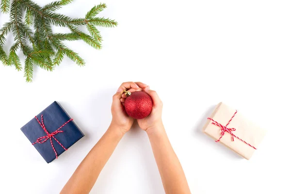 Bovenaanzicht van kid handen met decoratie van Kerstmis. Geschenkdozen en kerstboom tak op witte tafel — Stockfoto