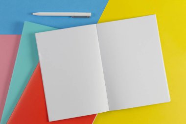 Açık defter, beyaz kalem ve mavi ve sarı arka plan üzerinde renkli Notebook