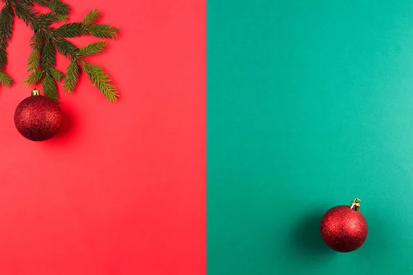 Rama del árbol de Navidad y bola de Navidad roja sobre fondo rojo y verde . — Foto de Stock