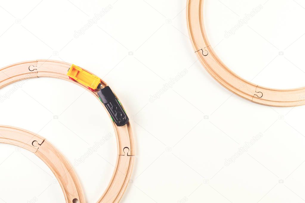Toy train and wooden rails on white background. Top view.
