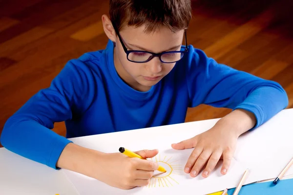 小男孩戴着眼镜与绘制彩色铅笔和毡笔 — 图库照片