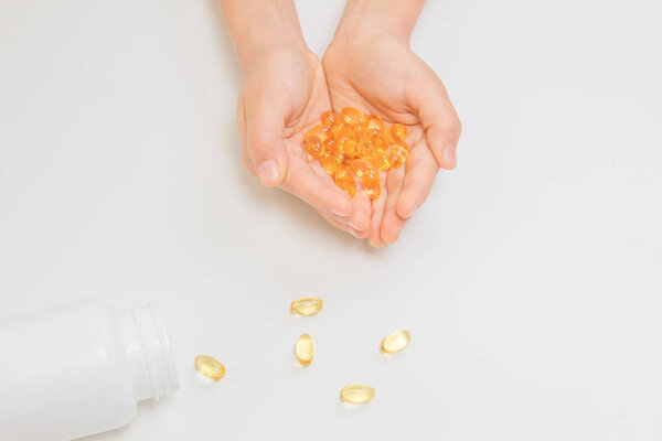 Fish oil omega 3 capsules in hands over white background