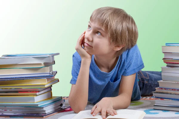 Boy čtení mezi Stoh knih. — Stock fotografie