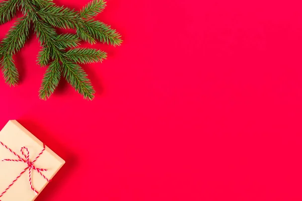 Christmas sammansättning på röd bakgrund. Gröna fir trädgren och nuvarande box — Stockfoto