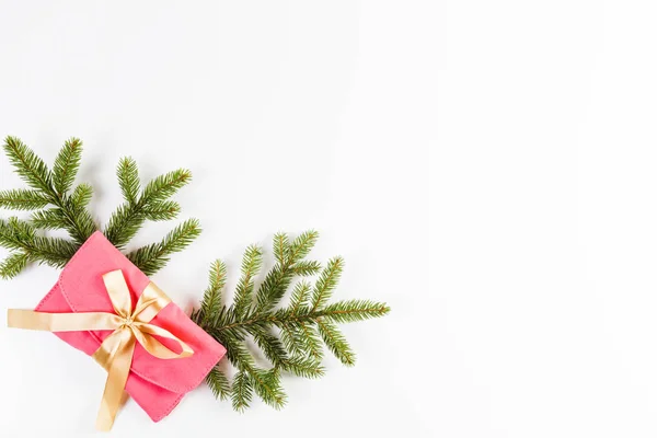 Karácsonyi háttér. Karácsonyi fa ága és a jelen fehér alapon arany szalaggal — Stock Fotó