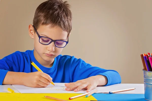 Menino com óculos desenhando com lápis coloridos e canetas de feltro — Fotografia de Stock