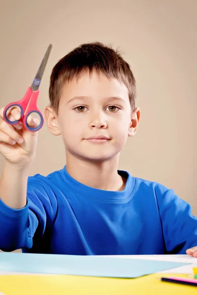 Ragazzo taglio carta colorata con forbici a tavola — Foto Stock