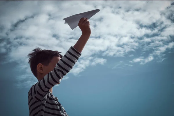 Chłopiec rzucanie biały papierowy samolot. — Zdjęcie stockowe
