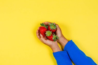 Çocuk ellerini tutarak taze çilek Sarı zemin üzerine