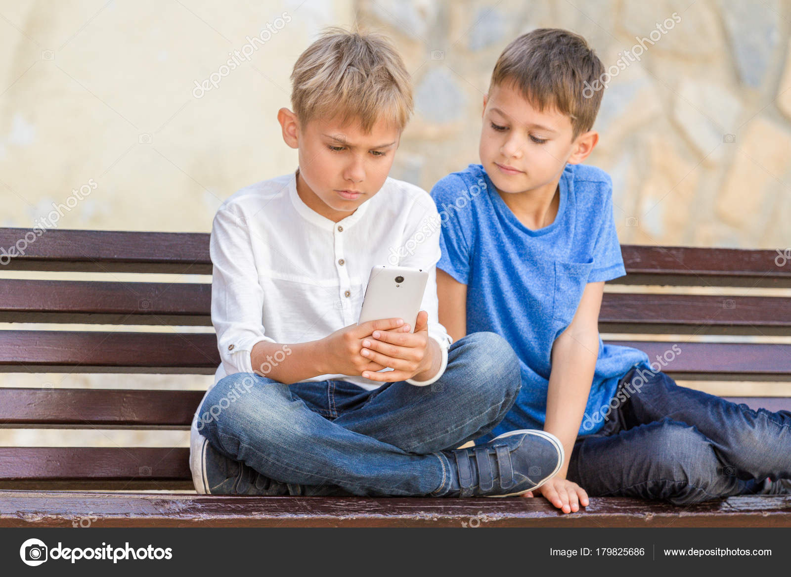 Boys With Mobile Phone Sitting On The Bench Outdoors Stock Photo