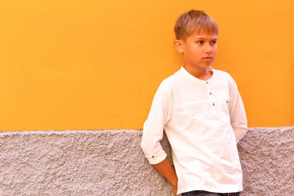 노란색 벽 근처에 서 멀리 보고 작은 소년 — 스톡 사진