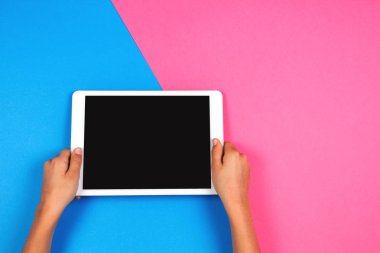 Tablet bilgisayarda pembe bir arka plan ile çocuk el.